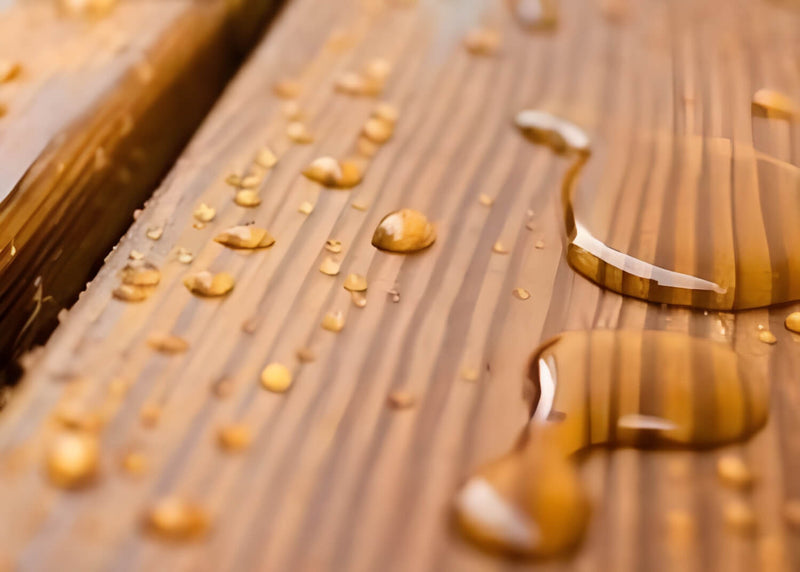 Close-up of a wooden surface with water droplets and a metal object.