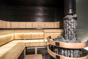 Modern sauna interior with wooden benches and a stone-lined smokestack.