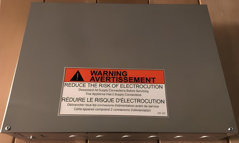 Metal box with a warning label in English and French on a wooden surface