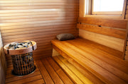 Wooden sauna with a bench and stone-filled sauna heater