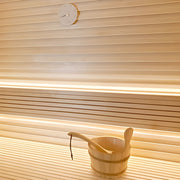 Wooden bucket with a ladle on a wooden floor with slatted walls.