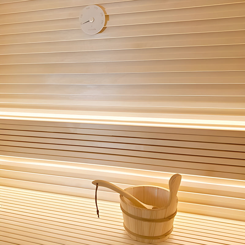 Wooden bucket with a ladle on a wooden floor with slatted walls.