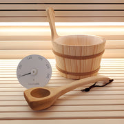 Wooden sauna bucket and ladle with a thermometer on a wooden surface