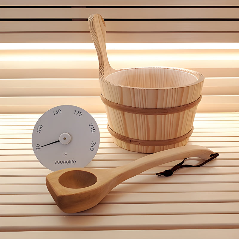 Wooden sauna bucket and ladle with a thermometer on a wooden surface