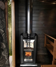 Wood-burning sauna heater in a dark wooden room with a bench and window.